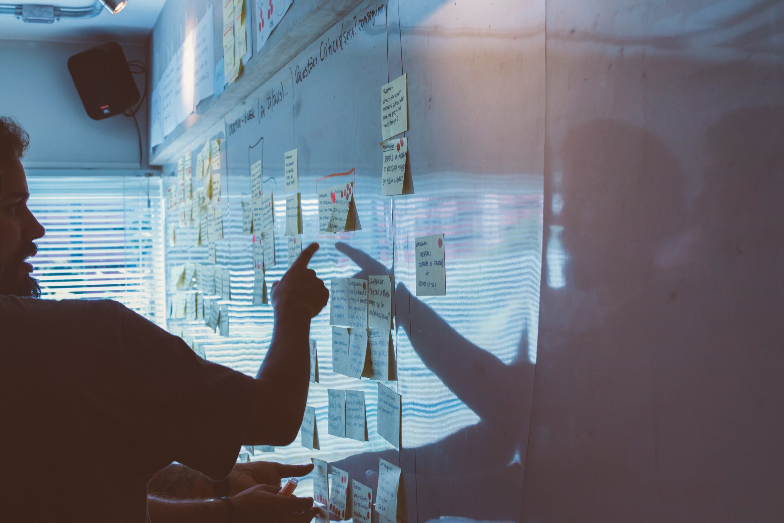 Man pointing to sticky notes on a white-board – representing employee engagement strategy in a small business. Image by Startae Team on Unsplash.